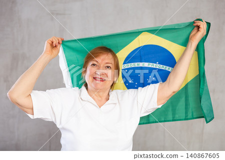 Happy senior woman holding flag of Brazil in studio Happy senior woman holding flag of Brazil in studio 140867605