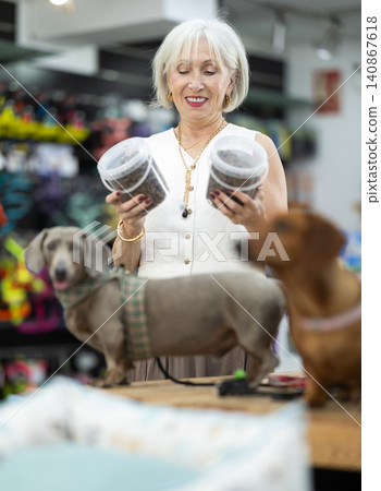 Elderly woman choosing dog food with dachshund in pet store Elderly woman choosing dog food with dachshund in pet store 140867618