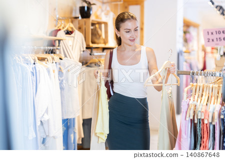 Young girl chooses something in branded clothing store Young girl chooses something in branded clothing store 140867648