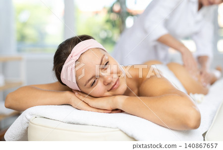 Young woman enjoying massage of thighs and buttocks in spa center Young woman enjoying massage of thighs and buttocks in spa center 140867657