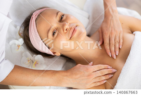 Young woman relaxing in spa salon during clavicles and neck massage Young woman relaxing in spa salon during clavicles and neck massage 140867663