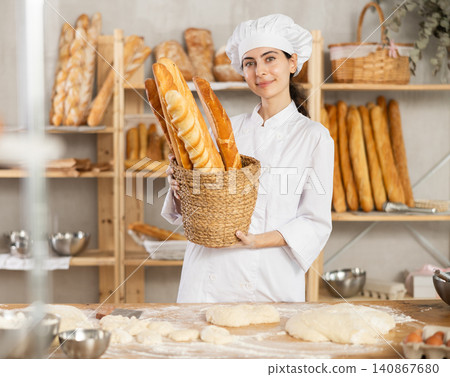 Young female baker with basket of baguettes Young female baker with basket of baguettes 140867680