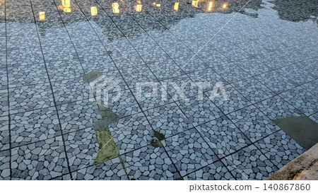 High angle full frame shot captures clean water rippling over a geometric gray mosaic stone tiled floor, creating beautiful reflections under soft evening illumination from small decorative square High angle full frame shot captures clean water rippling over a geometric gray mosaic stone tiled floor, creating beautiful reflections under soft evening illumination from small decorative square 140867860
