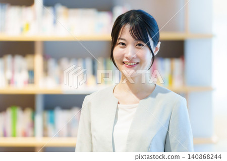 A woman standing in front of a bookshelf; author, novelist, essayist. A woman standing in front of a bookshelf; author, novelist, essayist. 140868244