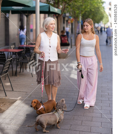 Senior woman and girl with pets walking in park Senior woman and girl with pets walking in park 140868526