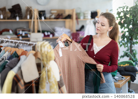 Young woman chooses warm dress in clothing store 140868528
