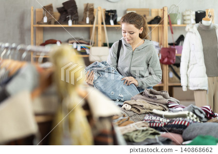 Young woman choosing jeans in clothing store Young woman choosing jeans in clothing store 140868662