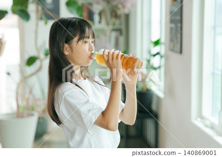 一個女孩用塑膠瓶喝大麥茶。 140869001