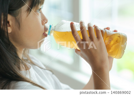 A girl drinking barley tea from a plastic bottle. A girl drinking barley tea from a plastic bottle. 140869002