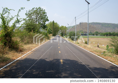 Asphalt rural road leads straight to the mountains ahead. Asphalt rural road leads straight to the mountains ahead. 140869130