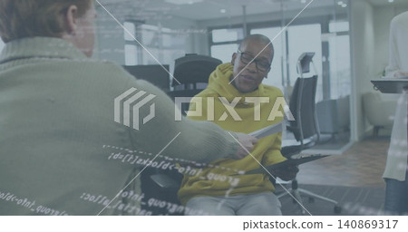 Receiving paper, man in yellow hoodie and glasses holding tablet at office with glass code overlay Receiving paper, man in yellow hoodie and glasses holding tablet at office with glass code overlay 140869317