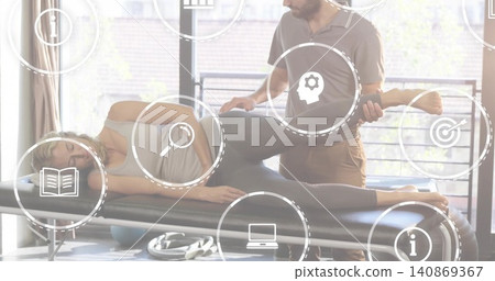 Supporting therapist in polo lifting patient's left leg on treatment table in clinic with icons Supporting therapist in polo lifting patient's left leg on treatment table in clinic with icons 140869367