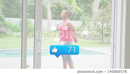 Standing woman in pink tank, gray leggings, looking up on pool deck via sliding-door with 71-badge Standing woman in pink tank, gray leggings, looking up on pool deck via sliding-door with 71-badge 140869576