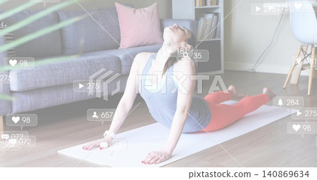 Stretching woman wearing blue tank and coral leggings on white mat at home, with social icons Stretching woman wearing blue tank and coral leggings on white mat at home, with social icons 140869634