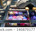 A water basin where brightly colored hydrangeas, illuminated by the light, float. 140870177