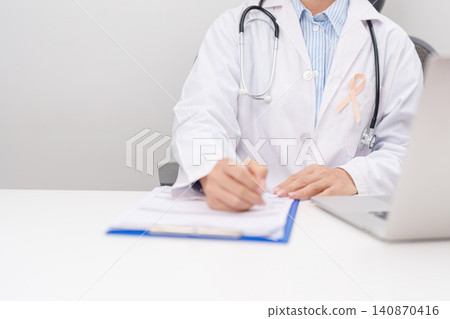 doctor using laptop and report notes on notebook. peach ribbon concept of September Uterine Cancer Awareness month, Endometrial, Gynecologic, Uterus and Ovaries, Endometriosis, June Vaginal cancer doctor using laptop and report notes on notebook. peach ribbon concept of September Uterine Cancer Awareness month, Endometrial, Gynecologic, Uterus and Ovaries, Endometriosis, June Vaginal cancer 140870416