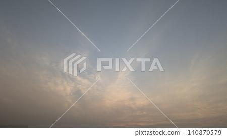 A horizontal wide angle perspective captures a beautiful clear sky filled with soft wispy clouds during a calm sunrise dawn period. The natural gradient color background creates a serene minimalist A horizontal wide angle perspective captures a beautiful clear sky filled with soft wispy clouds during a calm sunrise dawn period. The natural gradient color background creates a serene minimalist 140870579