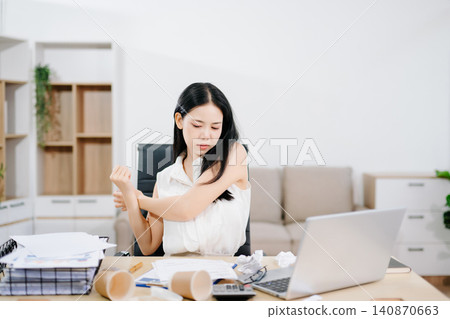 Young Asian woman suffering neck pain while working from home with laptop. Concept of stress, fatigue, burnout, workload and remote work challenges. Young Asian woman suffering neck pain while working from home with laptop. Concept of stress, fatigue, burnout, workload and remote work challenges. 140870663