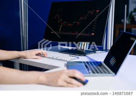 Focused trader reviewing financial charts and market data on multiple screens. Ideal for stock trading, investment, fintech, analytics, and business concepts. 140871087