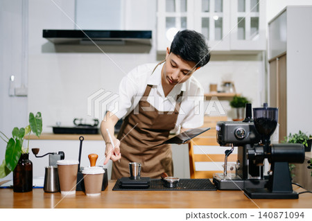 Male Asian barista using an espresso machine and taking notes on a clipboard in coffee shop. Male Asian barista using an espresso machine and taking notes on a clipboard in coffee shop. 140871094