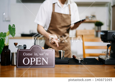 Professional cafe owner preparing coffee in a modern coffee shop with espresso machine and digital tablet, showcasing small business lifestyle Professional cafe owner preparing coffee in a modern coffee shop with espresso machine and digital tablet, showcasing small business lifestyle 140871095