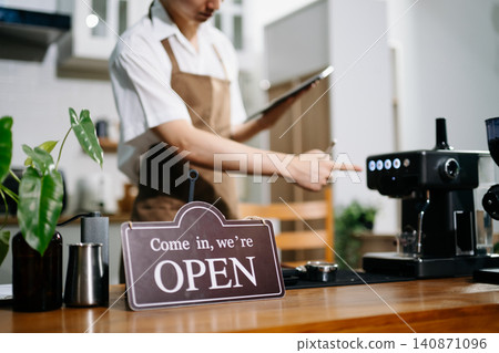 Professional cafe owner preparing coffee in a modern coffee shop with espresso machine and digital tablet, showcasing small business lifestyle Professional cafe owner preparing coffee in a modern coffee shop with espresso machine and digital tablet, showcasing small business lifestyle 140871096