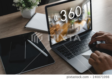 Hands using a laptop with a 360 virtual home tour on screen beside tablet and smartphone, viewing interior space for digital home presentation, remote browsing, and online exploration. Hands using a laptop with a 360 virtual home tour on screen beside tablet and smartphone, viewing interior space for digital home presentation, remote browsing, and online exploration. 140871098