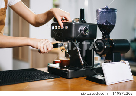 Cup and professional espresso machine pouring fresh coffee into a glass cup Cup and professional espresso machine pouring fresh coffee into a glass cup 140871202