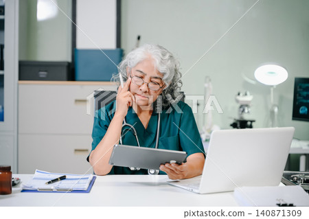 Senior doctor working on laptop in clinic, showcasing healthcare, medical technology, patient care, telemedicine, and professional expertise Senior doctor working on laptop in clinic, showcasing healthcare, medical technology, patient care, telemedicine, and professional expertise 140871309
