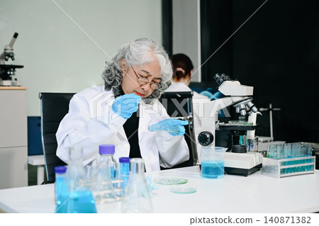 Two scientist or medical technician working, having a medical discuss meeting with an Asian senior female scientist supervisor in the laboratory with online reading, test samples and innovation Two scientist or medical technician working, having a medical discuss meeting with an Asian senior female scientist supervisor in the laboratory with online reading, test samples and innovation 140871382