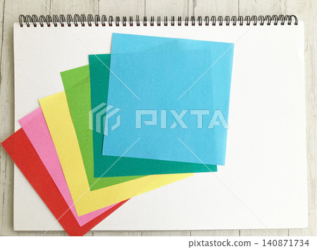 Colorful origami paper layered in a fan shape on a craft, educational, or arts/sketchbook. Colorful origami paper layered in a fan shape on a craft, educational, or arts/sketchbook. 140871734