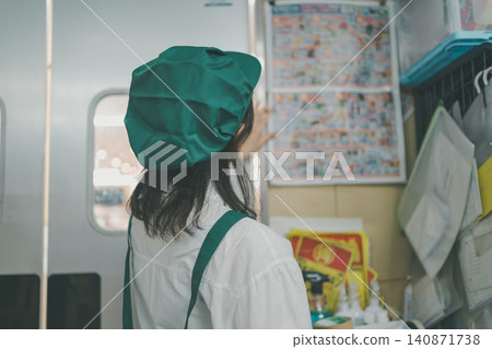 A female staff member's back is seen checking flyers posted on the wall in the back room of a supermarket. A female staff member's back is seen checking flyers posted on the wall in the back room of a supermarket. 140871738