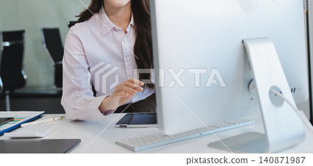 Young businesswoman professional employee using pc doing online banking analysing at workplace. Asian middle-aged business woman working on laptop computer in office, taking notes. Banner, copy space Young businesswoman professional employee using pc doing online banking analysing at workplace. Asian middle-aged business woman working on laptop computer in office, taking notes. Banner, copy space 140871987