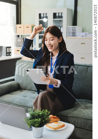 Asian businesswoman sitting at work using laptop talking and consulting in office Asian businesswoman sitting at work using laptop talking and consulting in office 140872015