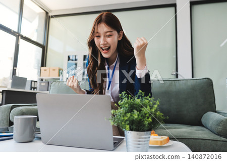 Asian businesswoman sitting at work using laptop talking and consulting in office Asian businesswoman sitting at work using laptop talking and consulting in office 140872016