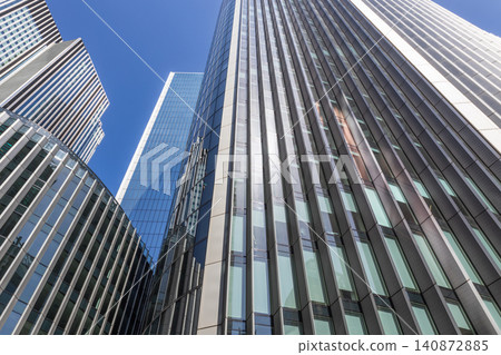 Looking up at glass and steel office buildings in city 140872885
