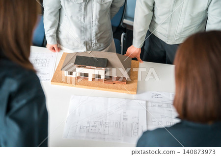 Male and female businessmen in work clothes from the construction and building industries use residential models for business negotiations, explanations, and presentations. Male and female businessmen in work clothes from the construction and building industries use residential models for business negotiations, explanations, and presentations. 140873973