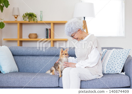 A senior woman holding a Chihuahua (family member) 140874409