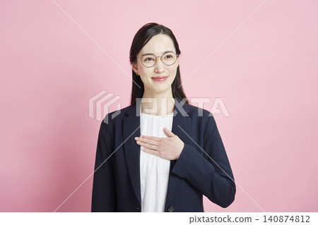 A smiling businesswoman wearing glasses against a pink background. A smiling businesswoman wearing glasses against a pink background. 140874812