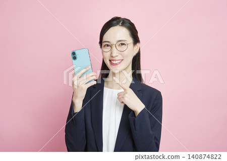Smiling business woman pointing at smartphone Smiling business woman pointing at smartphone 140874822