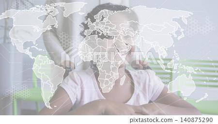 Smiling child in pink shirt sitting in wheelchair in clinic, guardian holding handles, map overlay 140875290