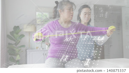 Guiding assistant aligning yellow tape across seated woman in purple top on bed, digital overlay Guiding assistant aligning yellow tape across seated woman in purple top on bed, digital overlay 140875337