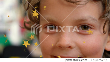 Smiling child with curly hair looking toward camera in playroom, with gold star stickers Smiling child with curly hair looking toward camera in playroom, with gold star stickers 140875753