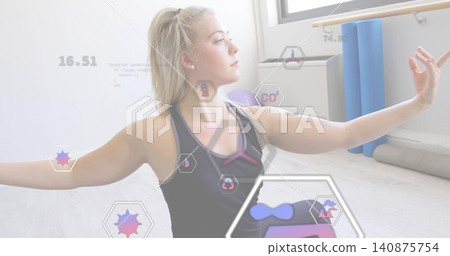 Stretching woman in dark tank top extending arms, gazing in studio with blue rollers, hex overlays Stretching woman in dark tank top extending arms, gazing in studio with blue rollers, hex overlays 140875754