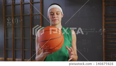 Holding woman green jersey white headband gripping orange basketball gym wooden bars math wall Holding woman green jersey white headband gripping orange basketball gym wooden bars math wall 140875928
