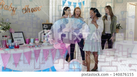 Holding mother wearing striped top showing baby outfit at home with Baby Shower banner and cupcakes Holding mother wearing striped top showing baby outfit at home with Baby Shower banner and cupcakes 140876155