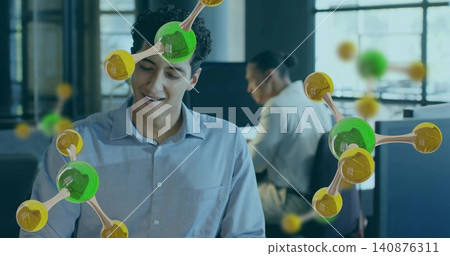 Smiling man wearing light-blue shirt reading at desks in open office, molecular overlays floating Smiling man wearing light-blue shirt reading at desks in open office, molecular overlays floating 140876311