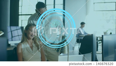 Smiling woman in sleeveless blouse looking at monitor, man leaning, pointing in office, HUD brain Smiling woman in sleeveless blouse looking at monitor, man leaning, pointing in office, HUD brain 140876320