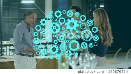 Discussing plan, trio in gray shirt, blazer around table with wine glasses, showing teal cog Discussing plan, trio in gray shirt, blazer around table with wine glasses, showing teal cog 140876324