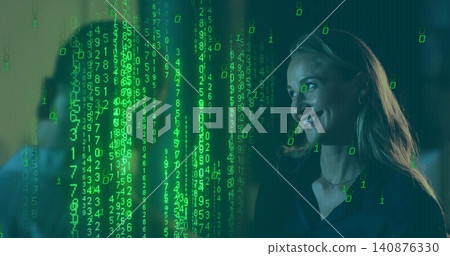Smiling woman wearing dark blouse, necklace watching green code projected across office, copy space Smiling woman wearing dark blouse, necklace watching green code projected across office, copy space 140876330